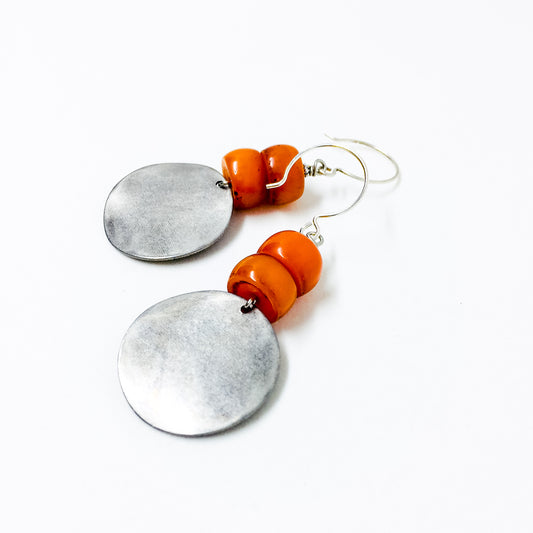Matte silver-tone discs and deep orange resin bead earrings